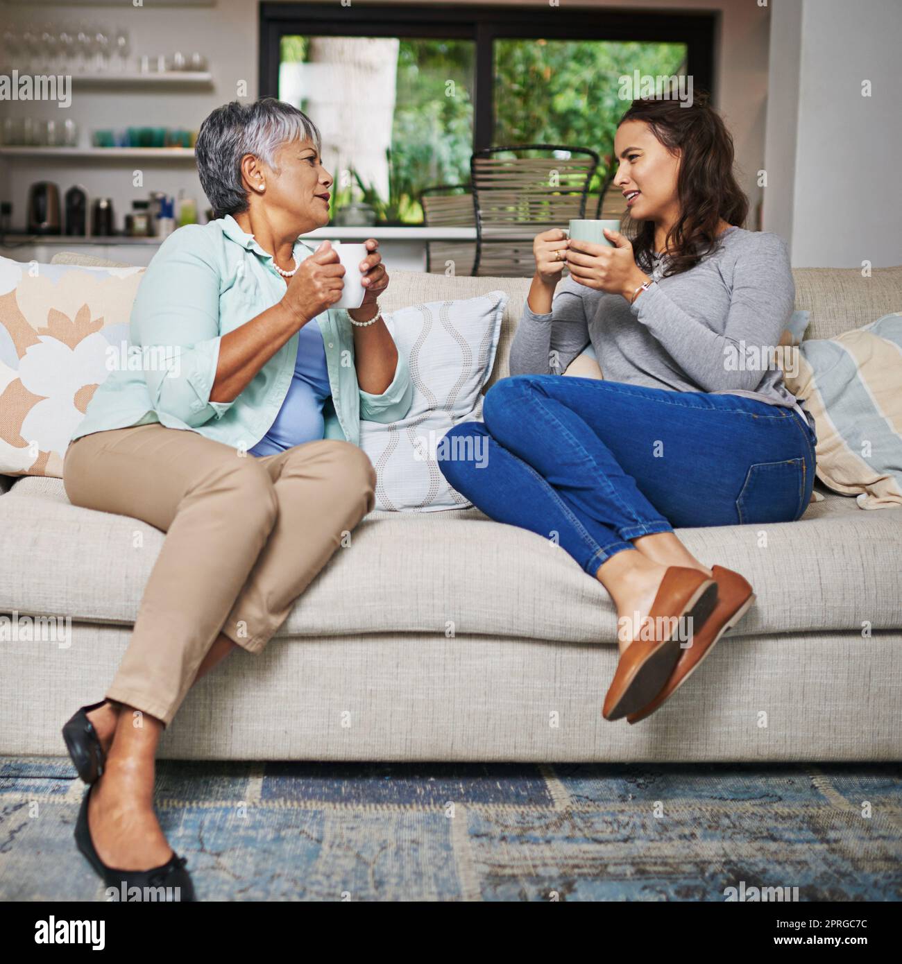 Wenn Sie nicht etwas nettes sagen können, junge Dame ... eine junge Frau und ihre Mutter, die auf dem Sofa aufholen, während sie Kaffee trinken. Stockfoto