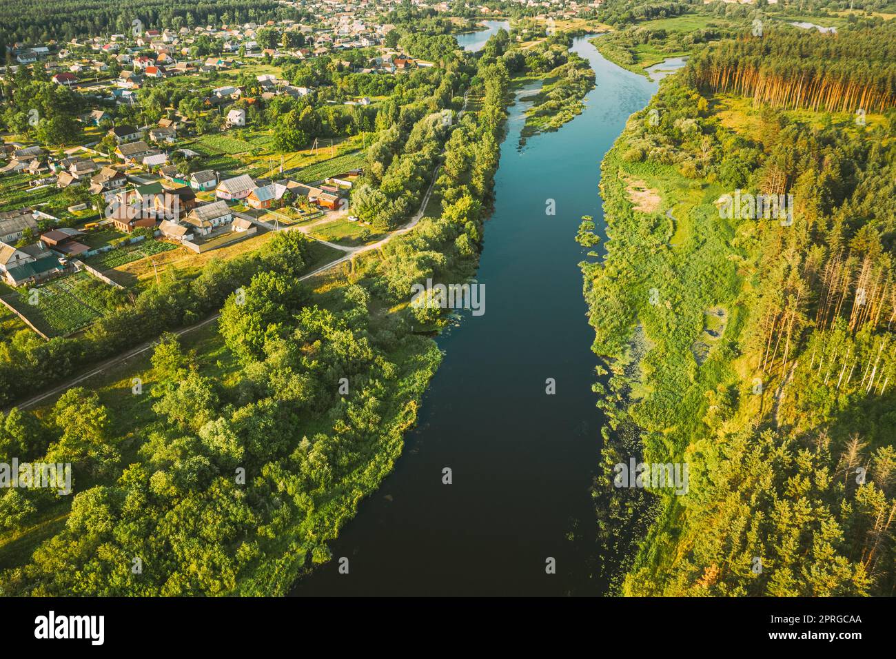 Luftaufnahme Des Calm River And Village In Weißrussland, Europa. Grüne Waldlandschaft Am Sonnigen Sommerabend. Blick Von Oben Auf Die Wunderschöne Europäische Natur Von High Attitude. Drohnenansicht. Vogelperspektive Stockfoto