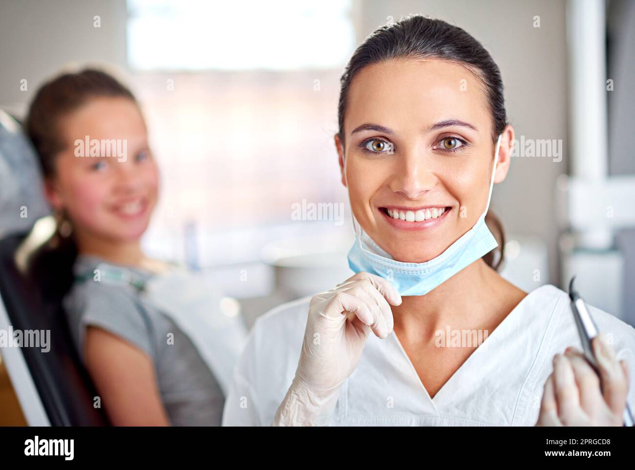 Sie ist großartig in dem, was sie tut. Porträt einer Zahnärztin mit ihrem Kind im Hintergrund. Stockfoto