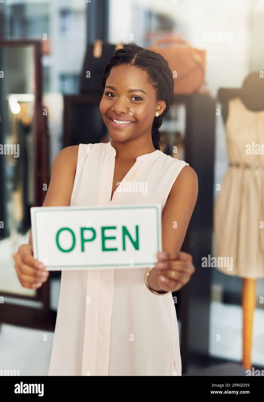 Kommen Sie vorbei und kaufen Sie unsere Verkäufe ein. Porträt einer jungen Geschäftsbesitzerin, die ein offenes Schild in ihrem Geschäft hält. Stockfoto