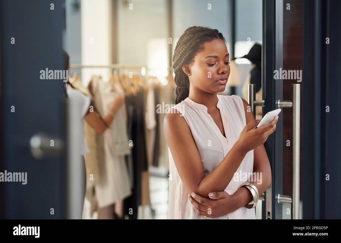 Kümmert sich um ein paar Arbeitstexte. Eine junge Geschäftsbesitzerin benutzt ein Handy in ihrem Laden. Stockfoto