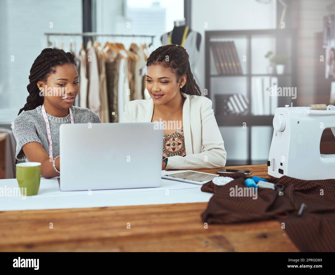 Sie sind bereit, einen neuen Trend zu starten. Zwei junge Modedesigner arbeiten an einem Laptop. Stockfoto