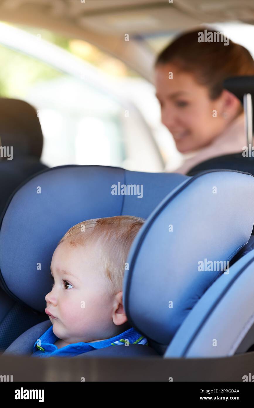 Sicher und bereit für ihre Reisen. Eine Mutter sitzt im Auto mit ihrem kleinen Jungen auf einem Autositz. Stockfoto