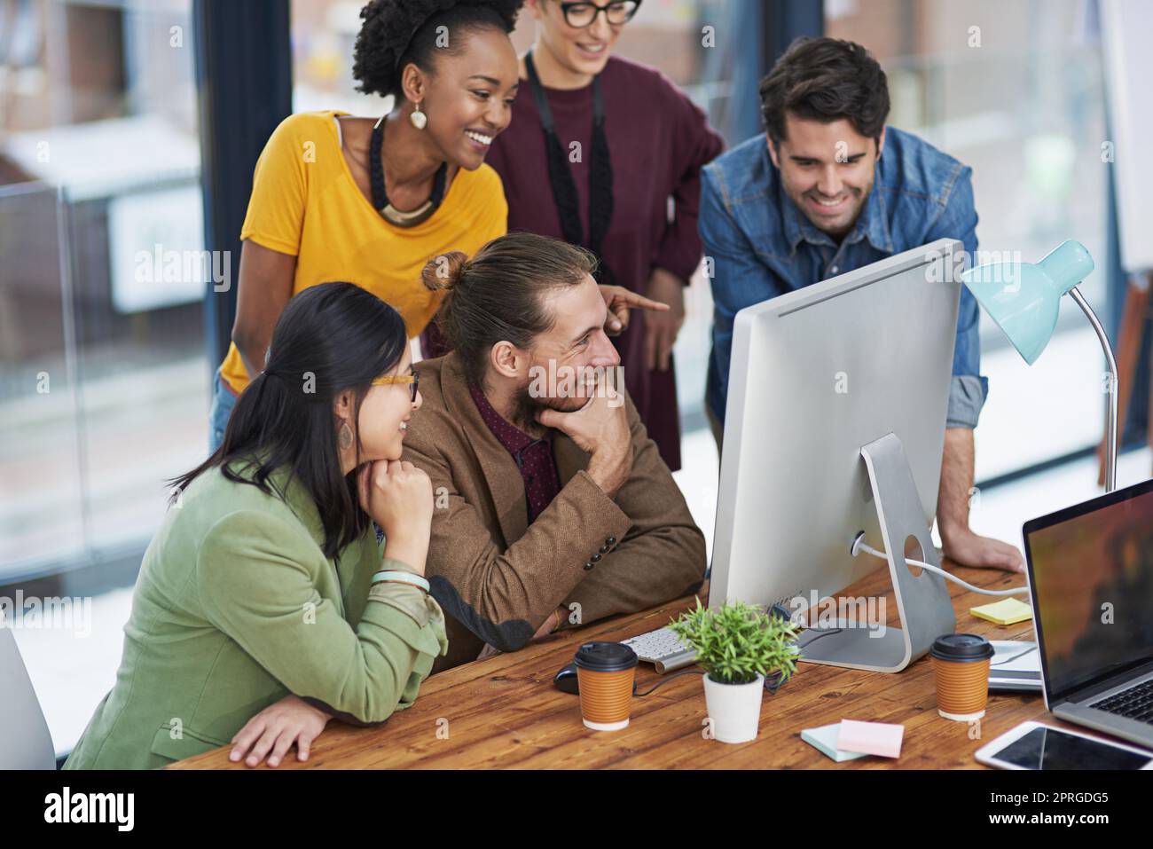 Motiviert durch ihren Wunsch zu erreichen. Eine Gruppe von kreativen Geschäftsleuten, die sich etwas auf einem Computer ansieht. Stockfoto