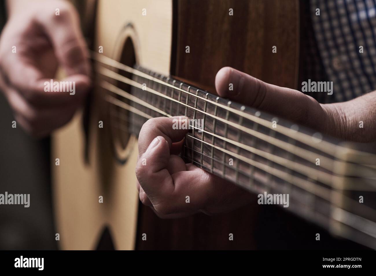 Jeder Akkord in der Melodie. Ein unkenntlich Mann spielt eine akustische Gitarre zu Hause. Stockfoto