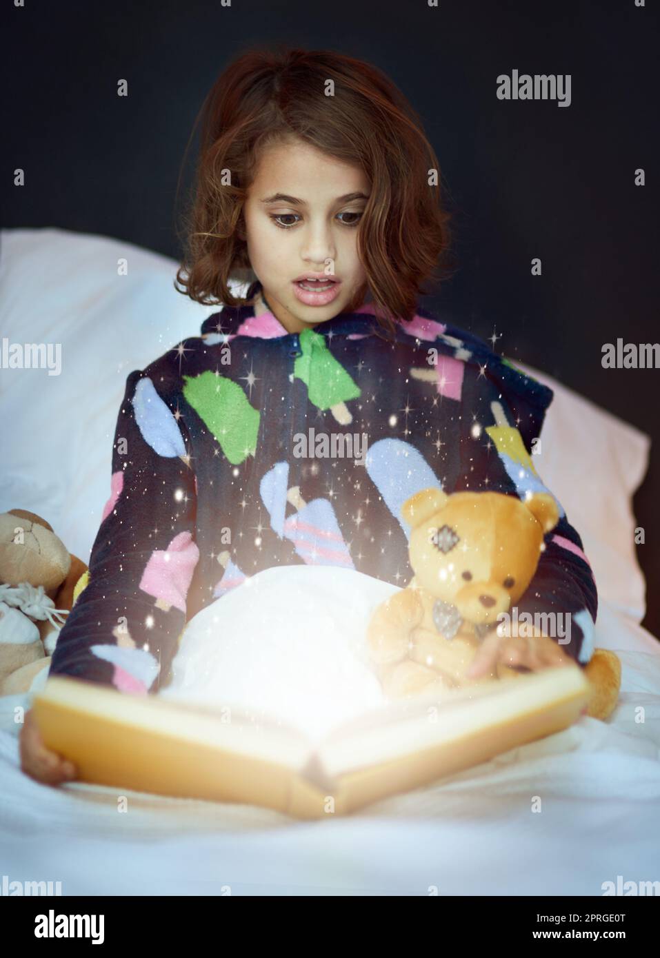 Die Magie des Lesens. Ein Mädchen liest ein Buch im Bett. Stockfoto