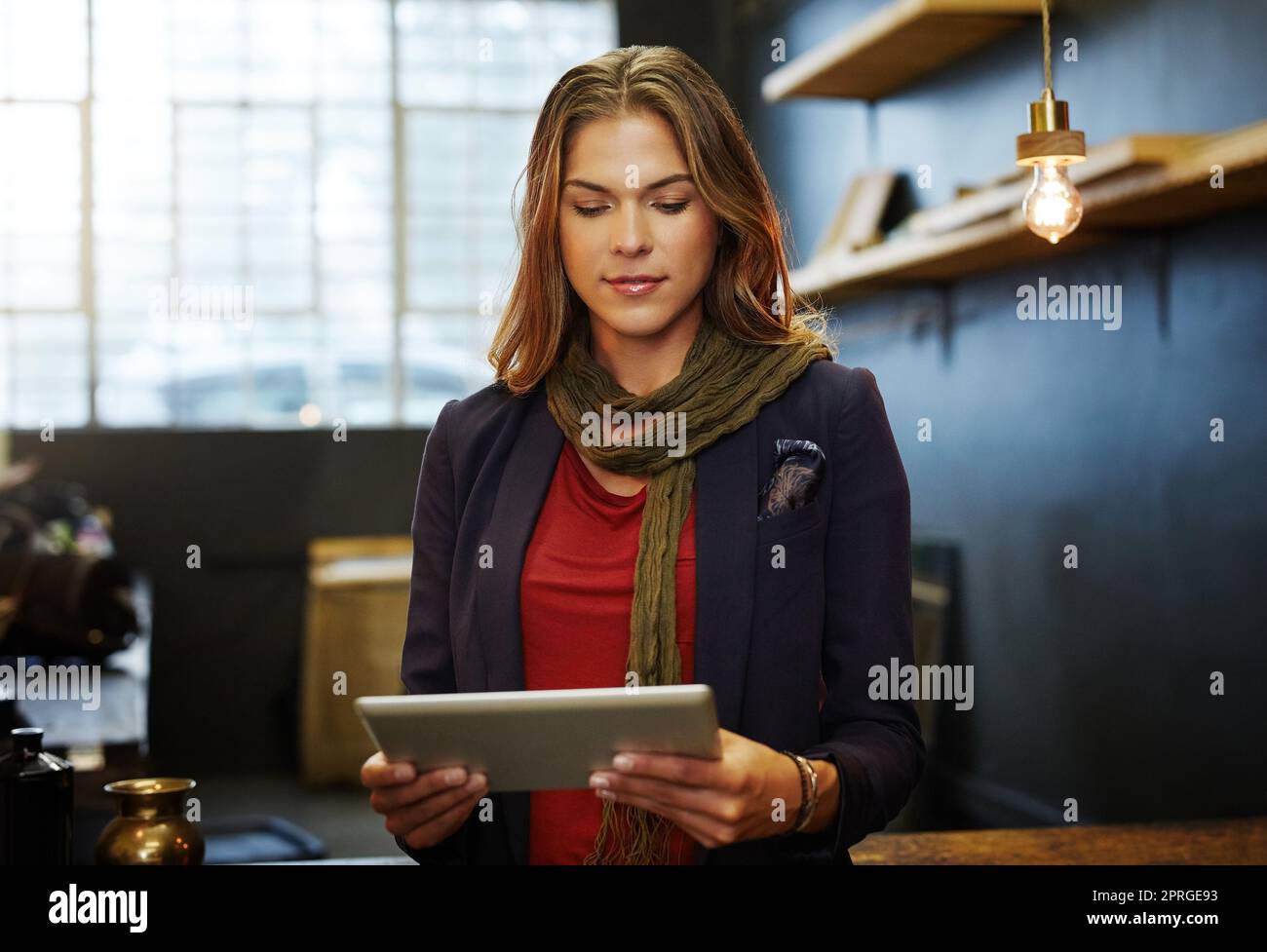 Gerade in meinem Tagebuch für den Tag. Eine junge Geschäftsbesitzerin mit einem digitalen Tablet in ihrem Shop. Stockfoto