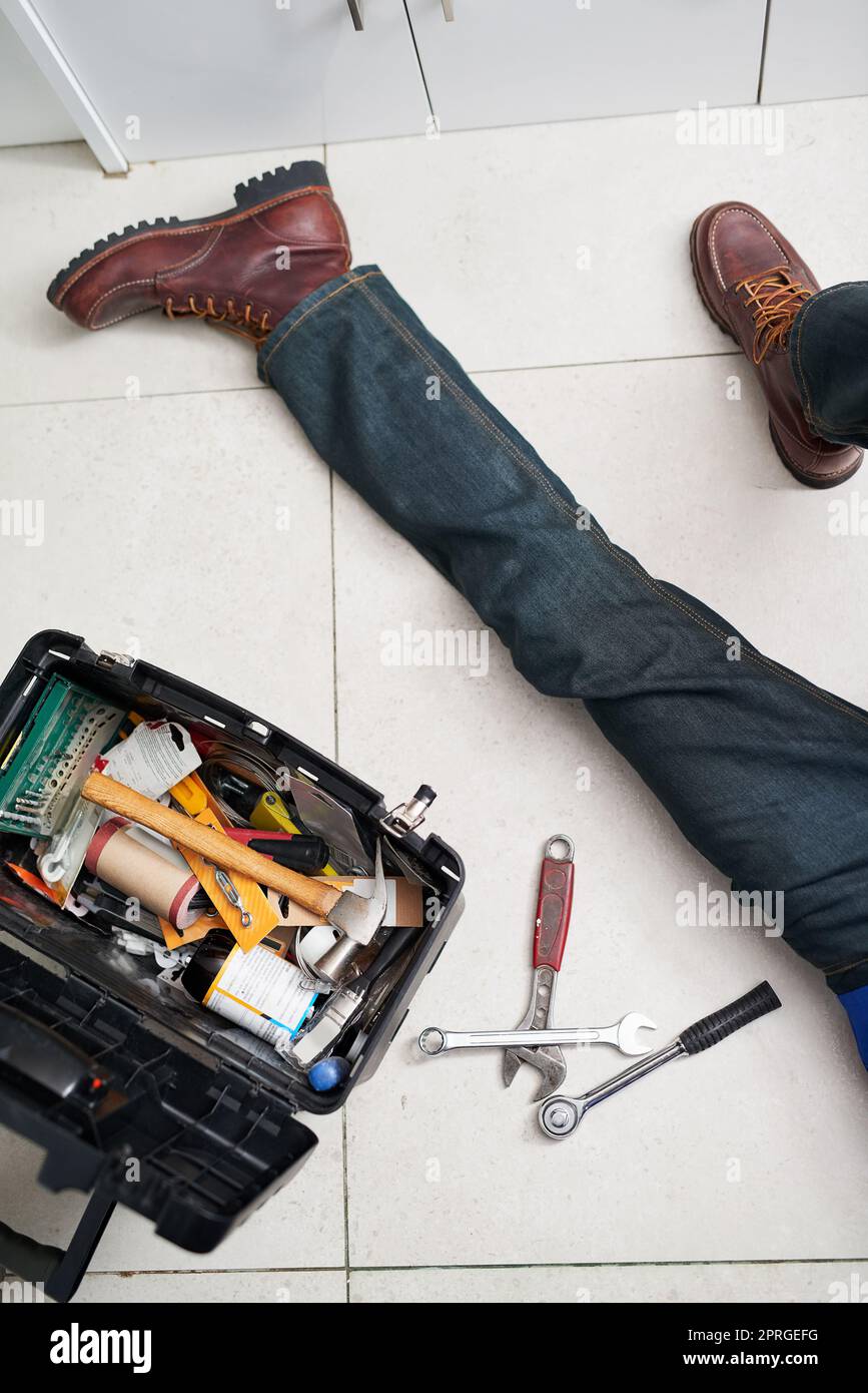 HES hat die Werkzeuge, um Ihre Sanitär-Anforderungen zu neigen. Ein Handwerker führt Reparaturen auf dem Boden neben seinem Werkzeugkasten. Stockfoto