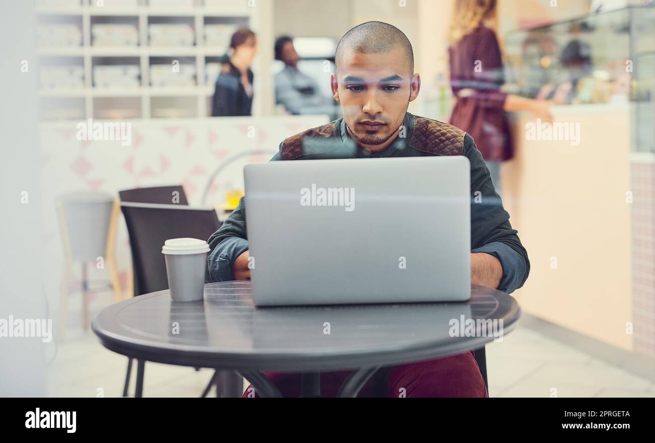 Kostenloses WLAN kann Wunder für Ihr Café tun. Ein junger Mann mit seinem Laptop in einem Café. Stockfoto