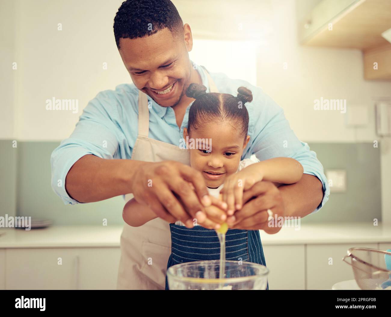 Glücklicher schwarzer Vater und glückliche Tochter, die in einer Küche backen, Spaß haben, verspielt zu sein und sich zu verbinden. Fürsorgliche Eltern, die Kindern Kochkünste und häusliche Fähigkeiten beibringen, bereiten gemeinsam einen gesunden, leckeren Snack oder eine Mahlzeit zu Stockfoto