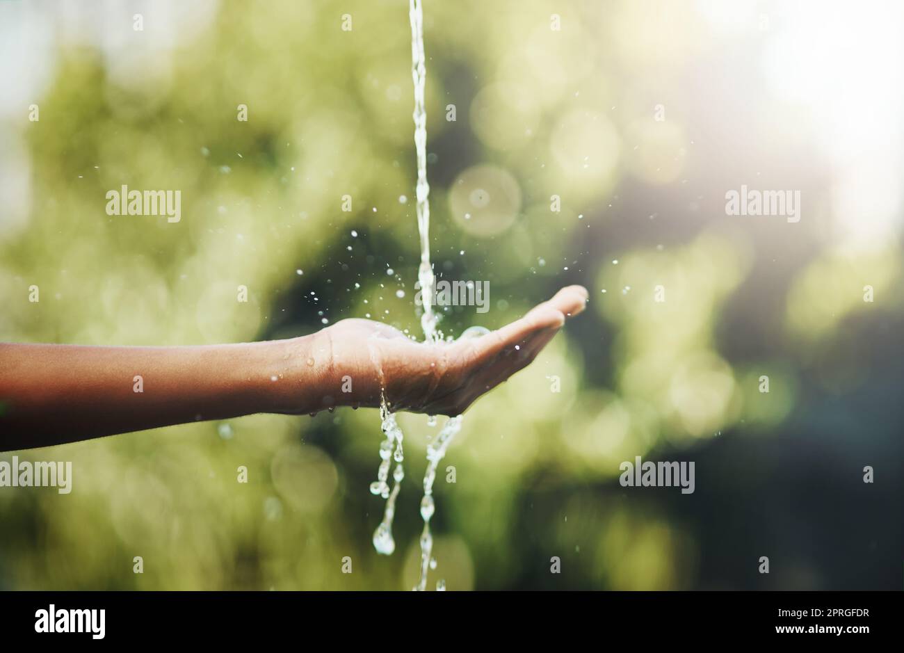 Jeder Tropfen ist kostbar. Hände werden ausgestreut, um draußen einen Wasserstrom zu fangen. Stockfoto