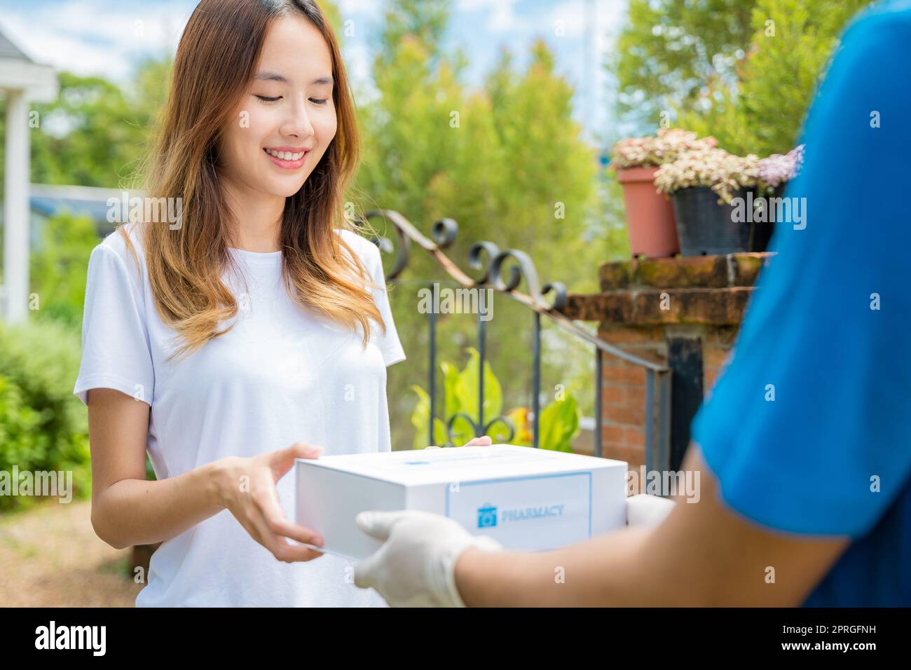 Kranke asiatische junge Frau erhalten Medizin erste Hilfe Apotheke Box vom Krankenhaus Lieferservice Stockfoto