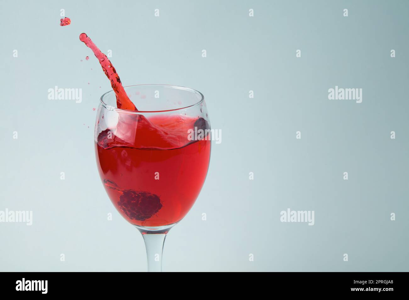 himbeere spritzt in Glas Wein roten Saft trinken Spritzer Wassertropfen auf weißem Hintergrund Stockfoto