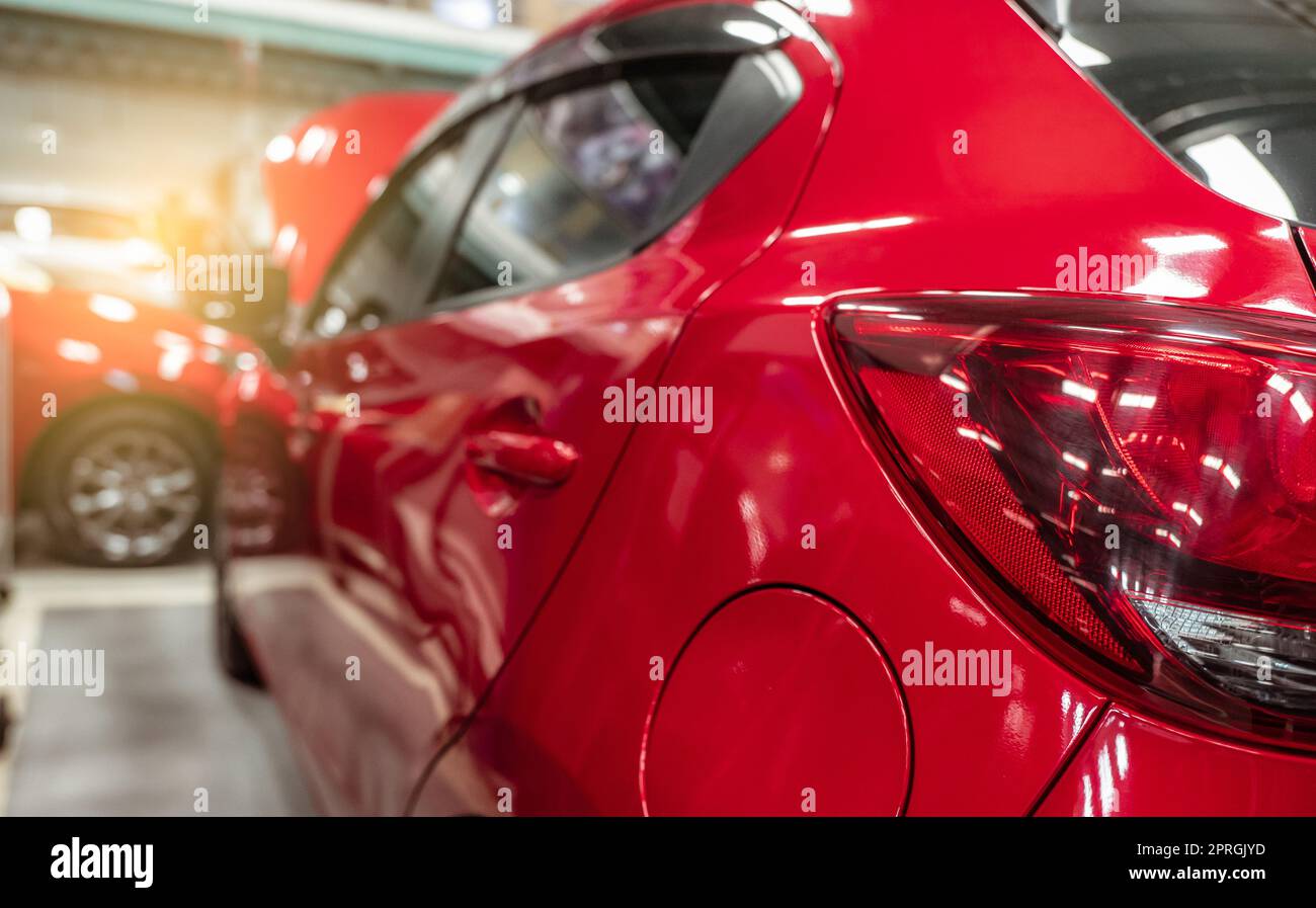 Rückansicht eines roten SUV, der in der Autoherstellung geparkt ist. Rotes Auto in der Werkstatt der Tankstelle. Fahrzeug in der Werkstatt. - Das ist ein Cleseup-Licht. Rotes Auto in der Garage für Reparatur- und Wartungsservice. Stockfoto