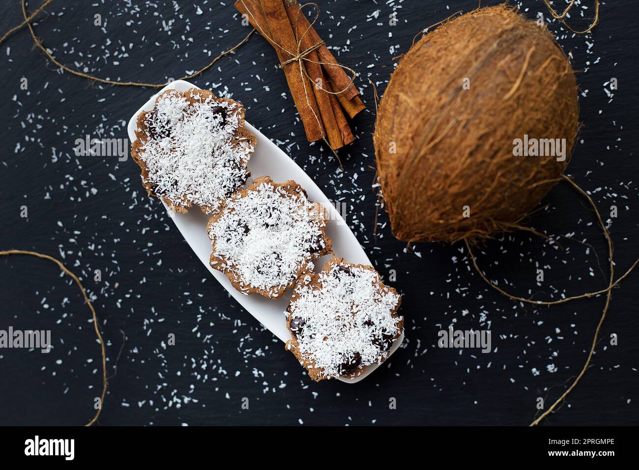 Kokos Muffins mit Schokolade auf einem schwarzen Hintergrund und ganze Kokosnuss Stockfoto