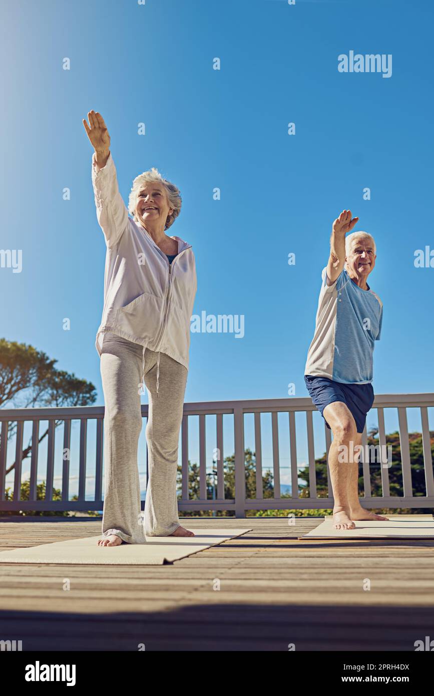 Verbesserung der Gesundheit in den goldenen Jahren. Ein Seniorenpaar macht gemeinsam Yoga auf ihrer Terrasse draußen. Stockfoto
