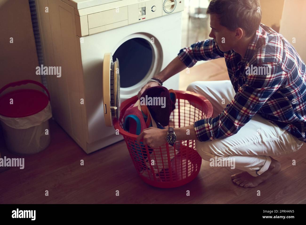 Ein junger Mann, der zu Hause Wäsche macht. Stockfoto