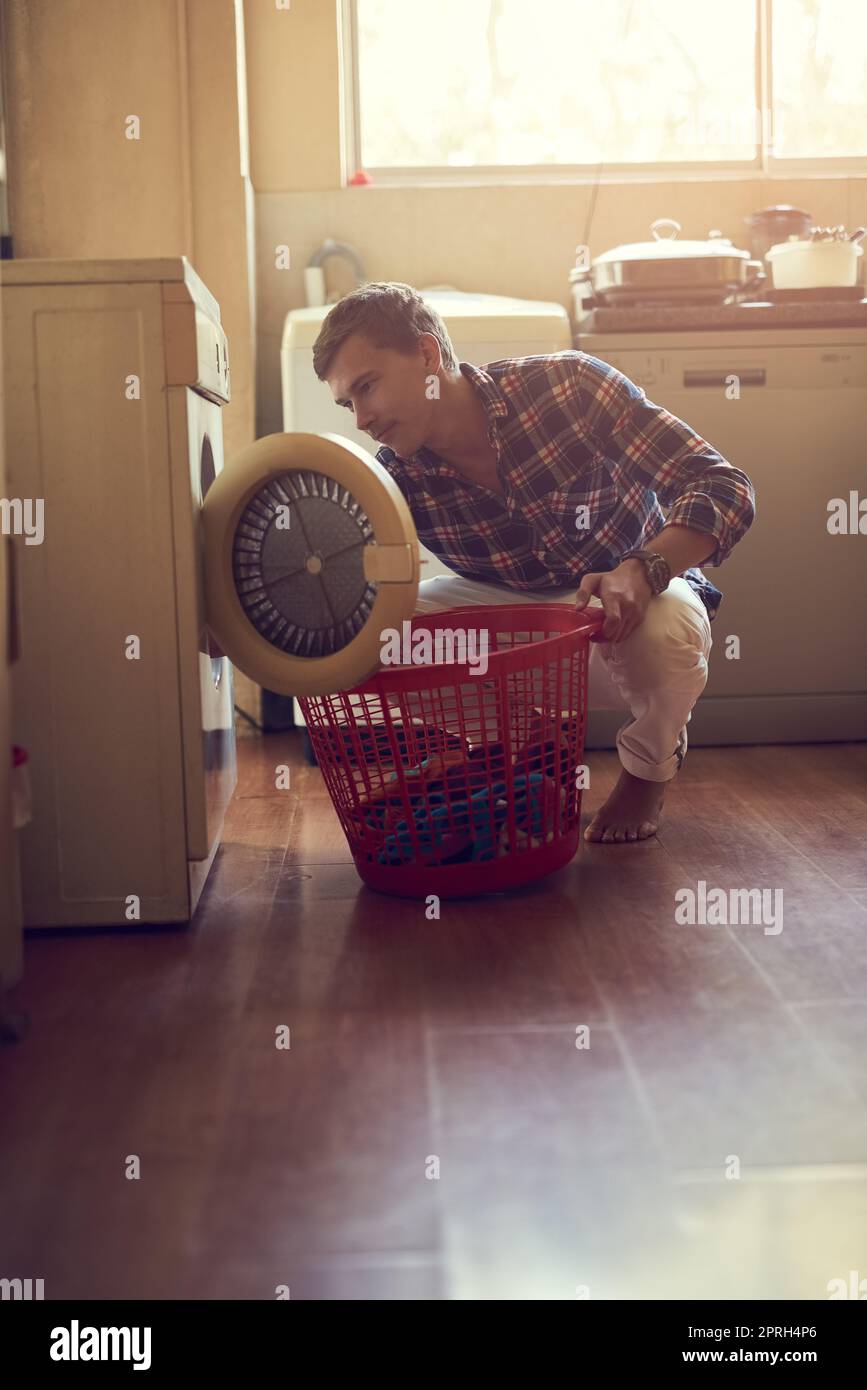 Die Kunst der Wäsche beherrschen. Ein junger Mann, der zu Hause Wäsche macht. Stockfoto