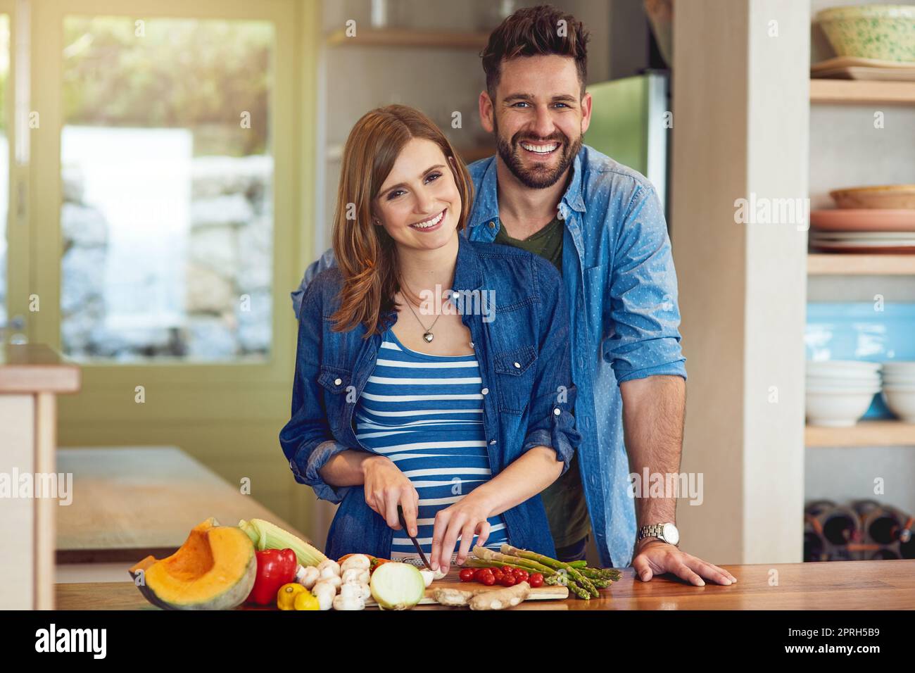 Herzgesundes Kochen für zwei Personen. Porträt eines glücklichen jungen Paares, das zu Hause gemeinsam eine gesunde Mahlzeit zubereitet. Stockfoto