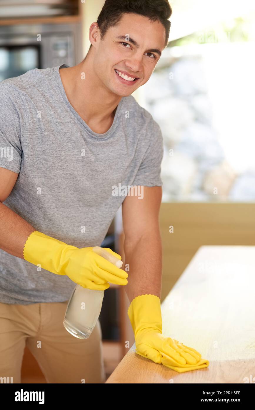 Spic und Span. Porträt eines glücklichen jungen Mannes, der seine Küche putzt. Stockfoto