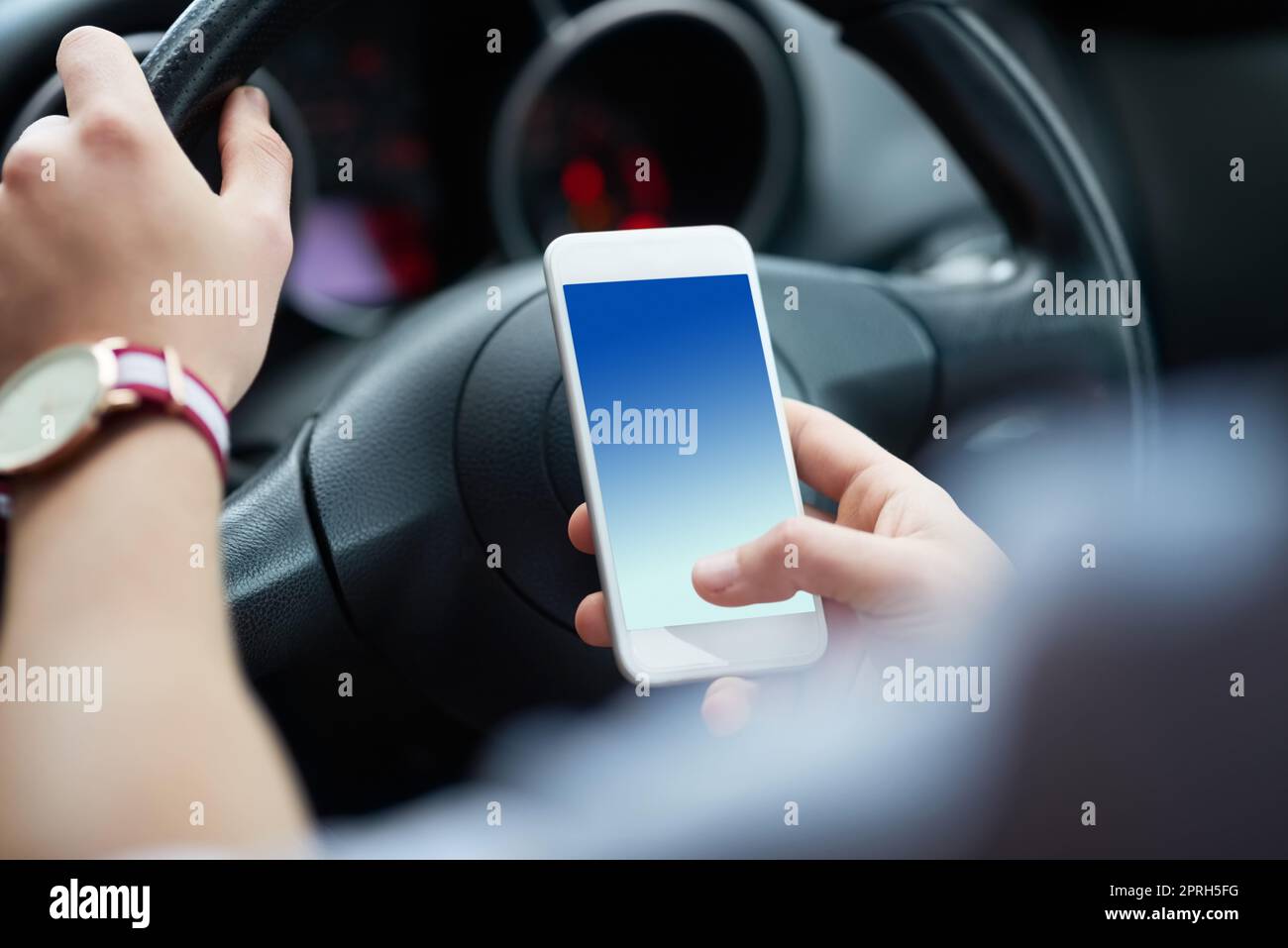 Ihr Telefon kann warten, aber Ihr Leben kann nicht mehr. Nahaufnahme eines nicht erkennbaren Mannes, der während der Fahrt sein Handy benutzt. Stockfoto