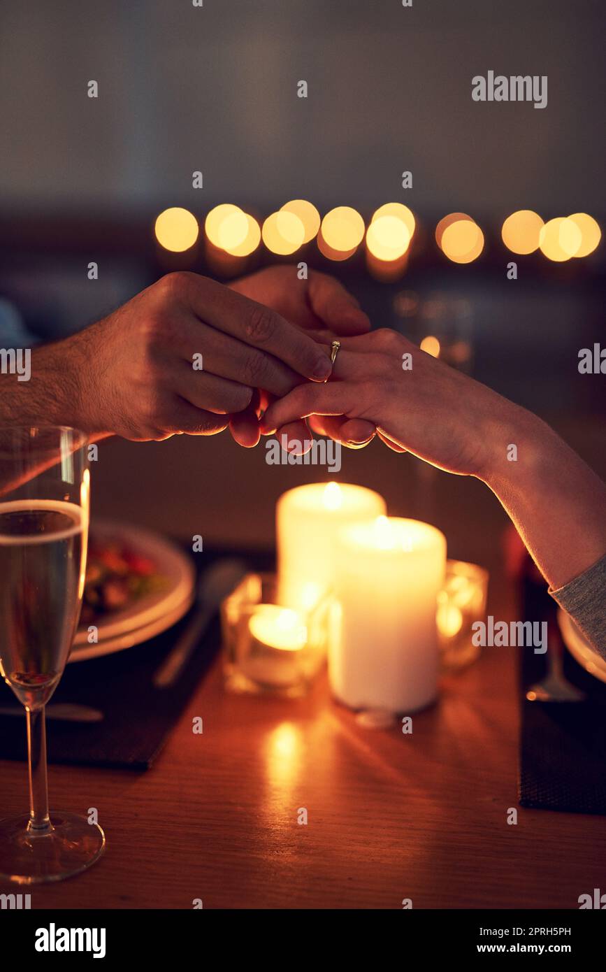 Es passt perfekt. Ein unverkennbarer Mann schlägt seiner Frau bei einem Candle-Light-Dinner in der Nacht vor. Stockfoto