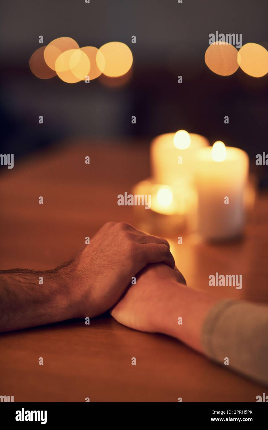 Alles wird gut werden, wenn wir zusammen sind. Nahaufnahme von zwei unbekannten Personen, die Hände über einem Esstisch halten, mit Kerzenlicht im Hintergrund. Stockfoto