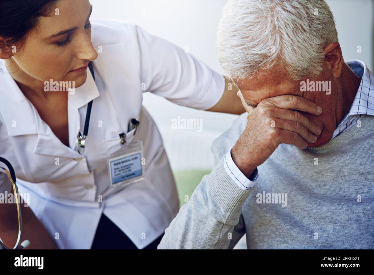 Die Pflege von Patienten mit Mitgefühl. Ein Betreuer tröstet einen depressierten älteren Mann. Stockfoto