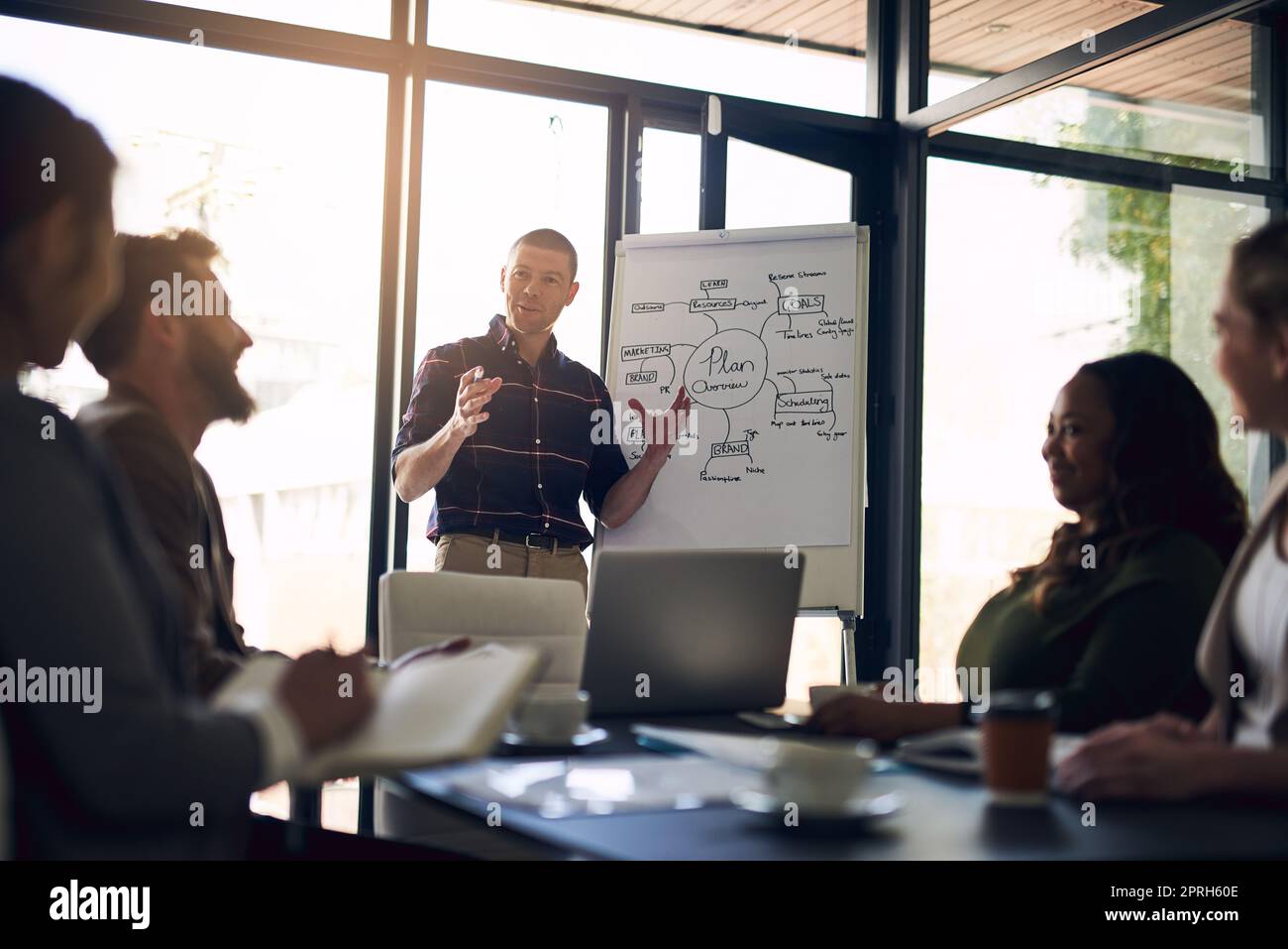 Wir müssen überdenken: Ein motivierter Geschäftsmann, der eine Präsentation vor Arbeitskollegen in einem Vorstandszimmer vorstellt. Stockfoto
