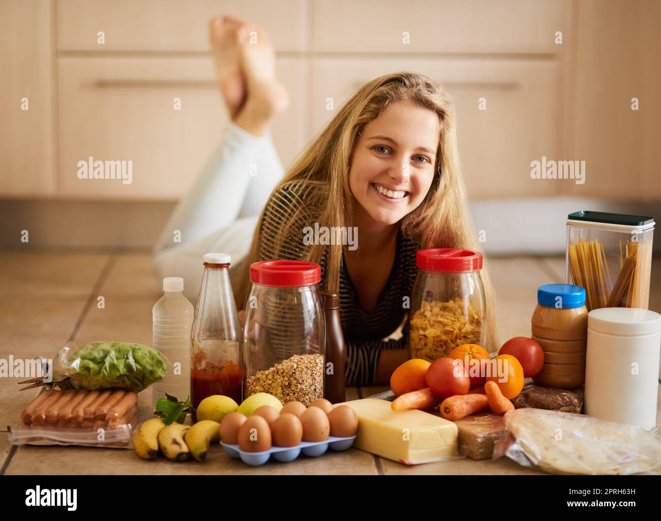 Ich trete gesunde Entscheidungen, wenn es um mein Essen geht. Eine attraktive junge Frau, umgeben von verschiedenen Lebensmitteln in der Küche zu Hause. Stockfoto