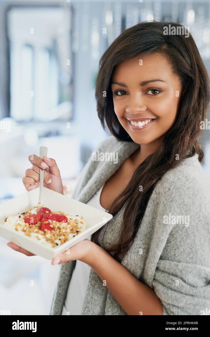Gesund essen und sich großartig fühlen. Porträt einer glücklichen jungen Frau, die zu Hause ein gesundes Frühstück genießt. Stockfoto
