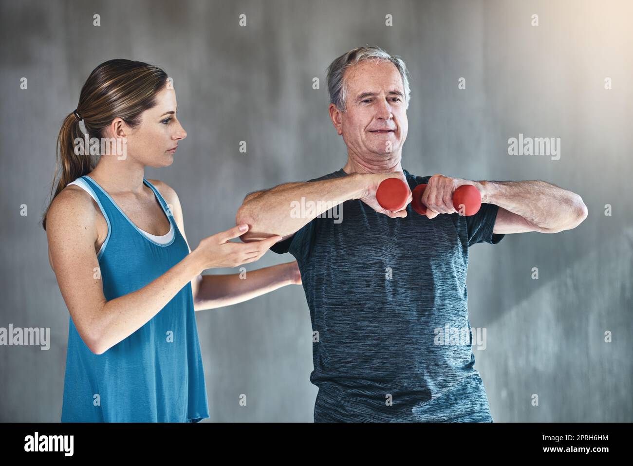 Verpflichtet, in jedem Alter aktiv und stark zu bleiben. Ein älterer Mann, der Gewichte mit Hilfe eines Physiotherapeuten verwendet. Stockfoto