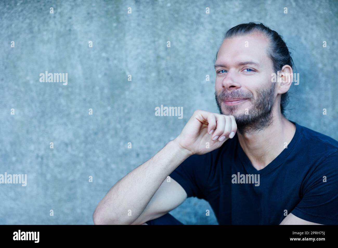 Nehmen Sie sich Zeit zum Entspannen. Porträt eines Mannes, der draußen an einer Wand sitzt. Stockfoto