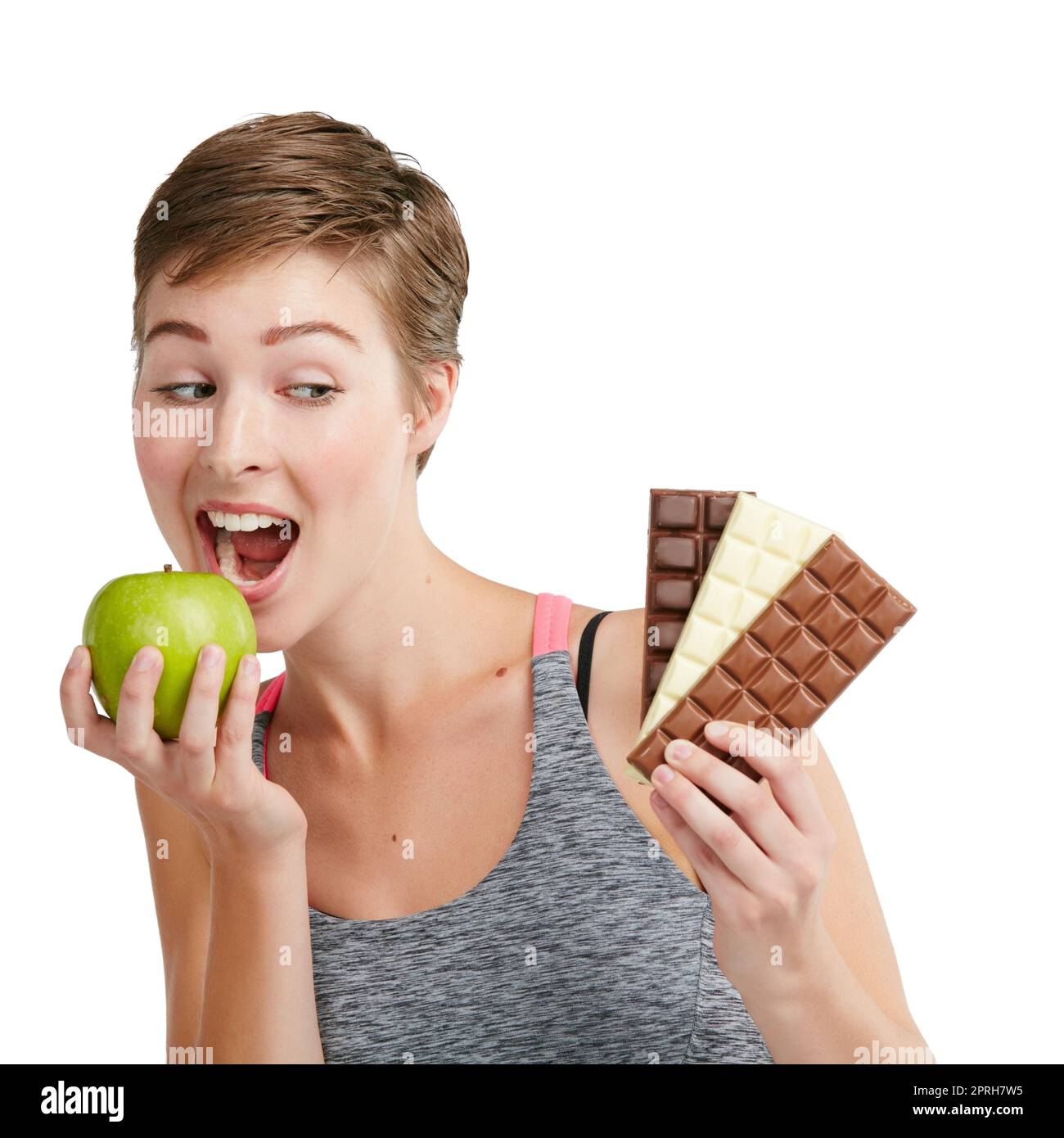 Ändere deine Meinung, verändere deinen Körper. Studio-Aufnahme einer jungen Frau, die sich für den Verzehr von Schokolade oder einem Apfel vor weißem Hintergrund entscheidet. Stockfoto