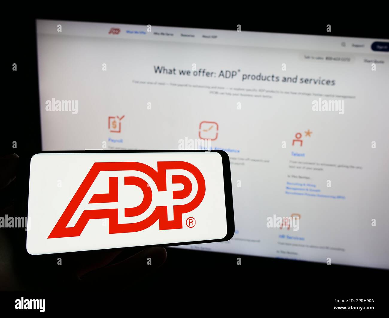 Person, die ein Mobiltelefon mit dem Logo der amerikanischen Firma Automatic Data Processing Inc. Besitzt (ADP) auf dem Bildschirm vor der Webseite. Konzentrieren Sie sich auf das Display des Telefons. Stockfoto