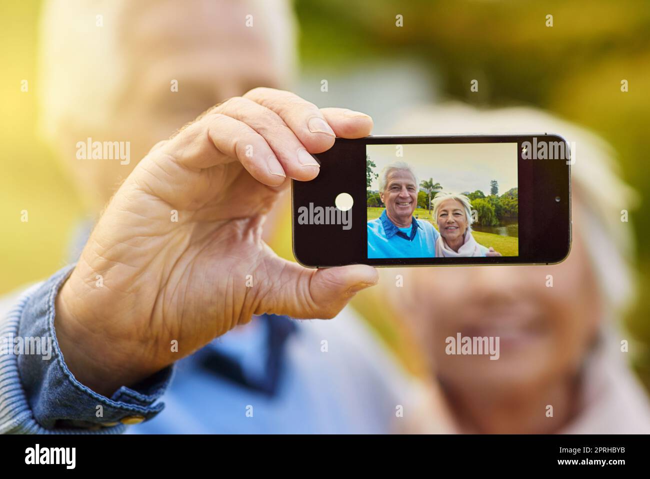Nun, fügen Sie diese zu unserem Fotoalbum. Ein Seniorenpaar, das ein Foto zusammen in einem Park. Stockfoto