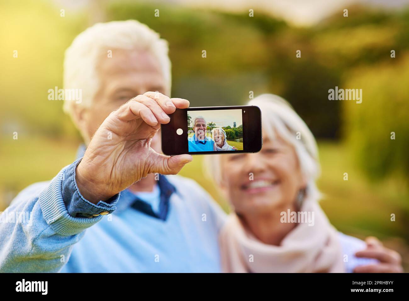 Fröhliche Momente. Ein Seniorenpaar, das zusammen in einem Park ein Foto gemacht hat. Stockfoto