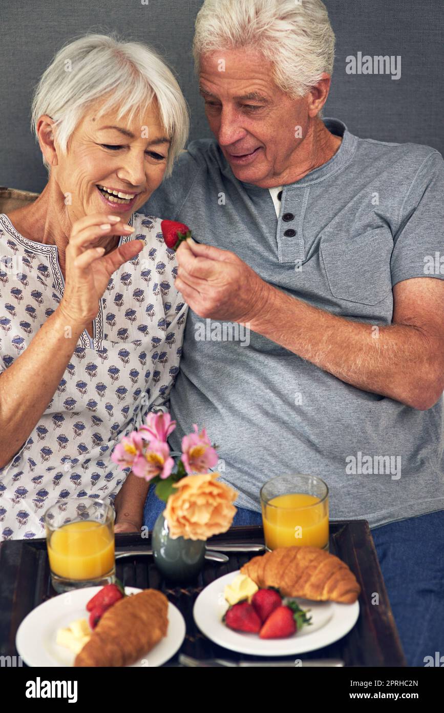 Alles Glück hängt von einem gemütlichen Frühstück ab. Ein älteres Paar, das im Bett frühstückt. Stockfoto
