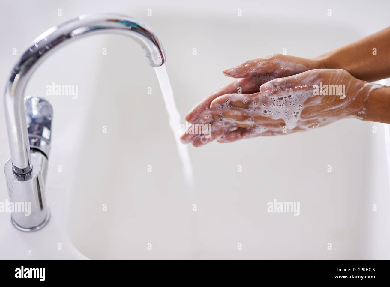 Eine Frau, die sich an einem Waschbecken die Hände wäscht. Stockfoto