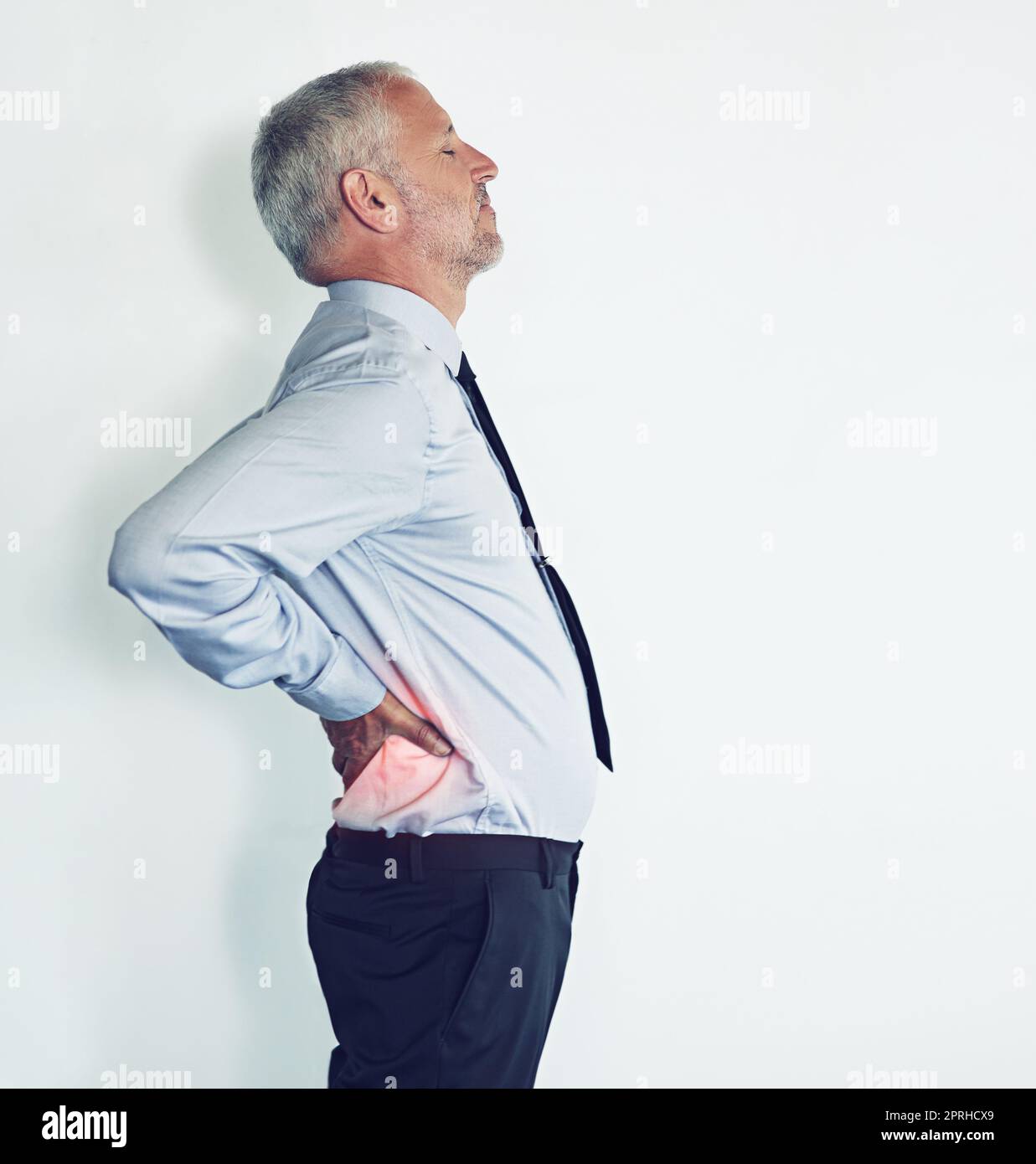 Die Auswirkungen von Stress nach der Arbeit. Studioaufnahme eines reifen Mannes, der Rückenschmerzen vor weißem Hintergrund erlebt. Stockfoto