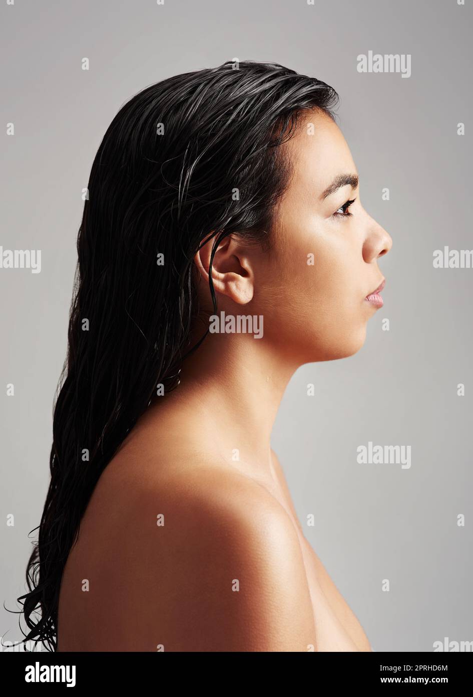 Natürlich schön in jedem Winkel. Studioaufnahme einer jungen Frau mit nassem Haar, die vor grauem Hintergrund posiert. Stockfoto