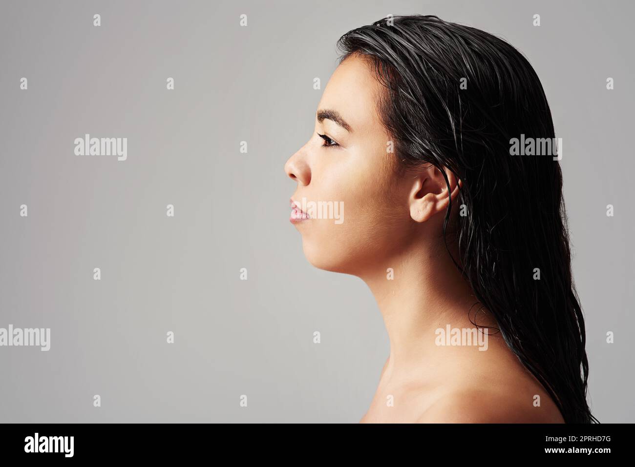 Frisch und sauber. Studioaufnahme einer jungen Frau mit nassem Haar, die vor grauem Hintergrund posiert. Stockfoto