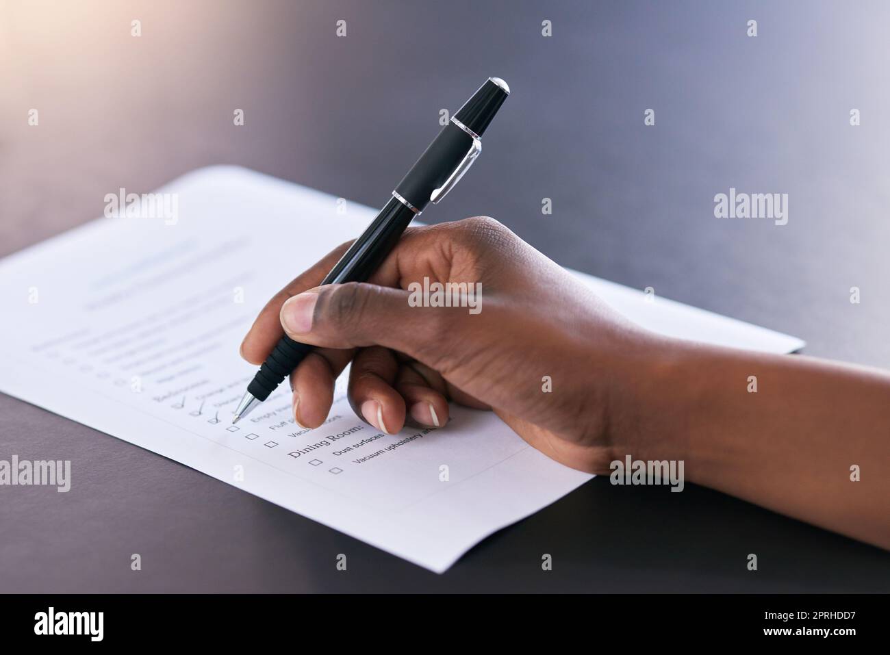 Eine Frau markiert abgeschlossene Aufgaben auf einer Liste von Aufgaben. Stockfoto