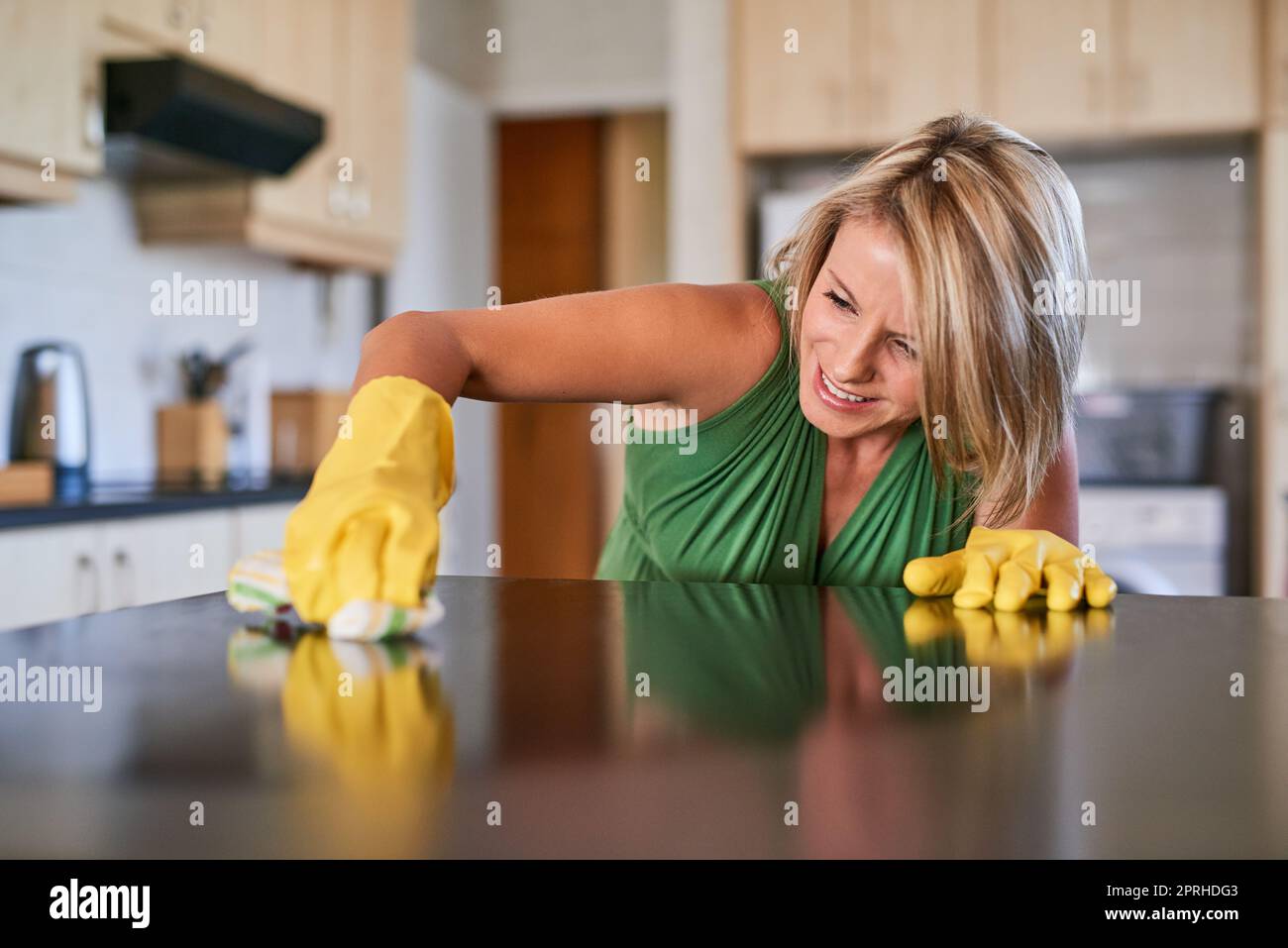 Hartnäckige Flecken loszuwerden. Eine junge Frau, die eine Küchenoberfläche reinigt. Stockfoto