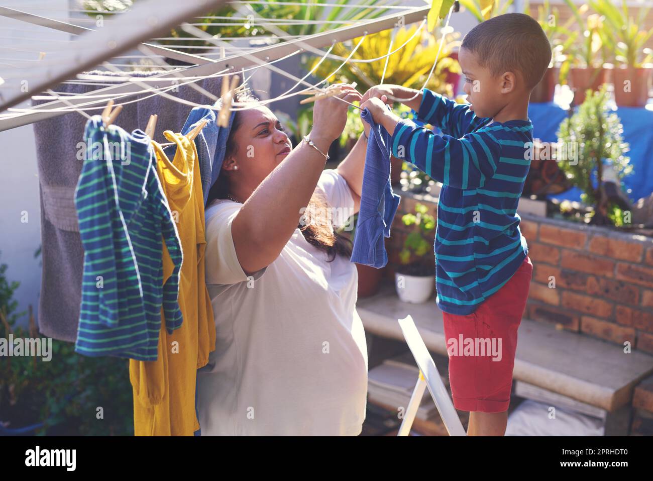 Eine Mutter und ein Sohn hängen draußen an einer Wäscheleine. Stockfoto