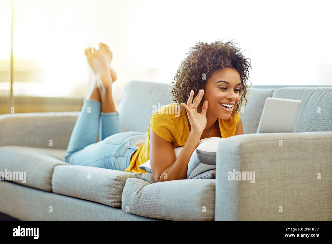 Hey, wie geht es dir. Eine junge Frau chattet zu Hause auf ihrem Tablet. Stockfoto