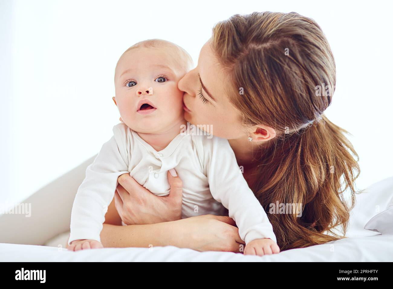 Küsst, kuschelt und kuschelt sich. Eine junge Mutter, die sich zu Hause mit ihrem entzückenden Jungen anschließt. Stockfoto