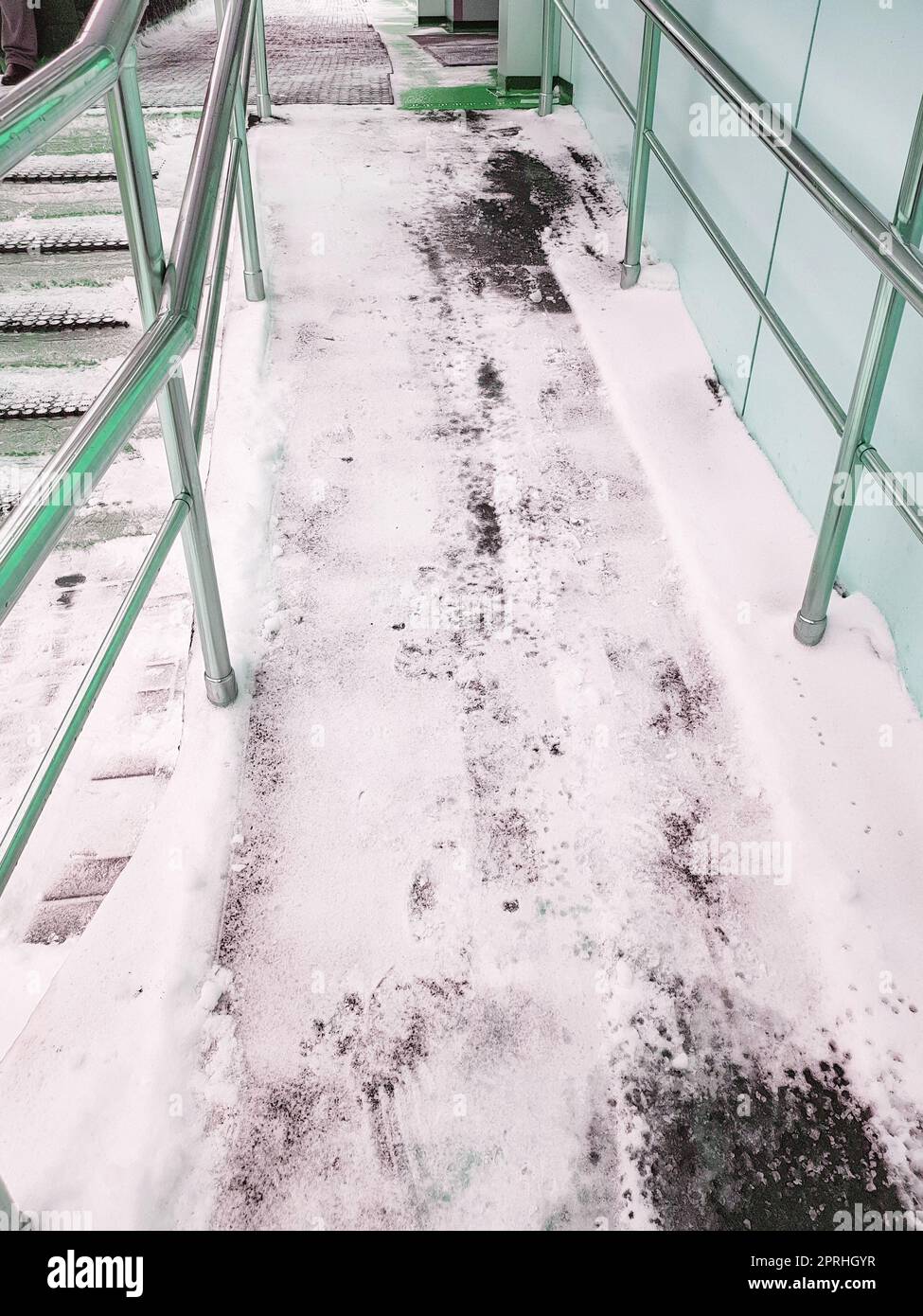 Moderne Rampe mit Metallgeländern für behinderte Menschen, schneebedeckte Rampe, vertikales Foto Stockfoto