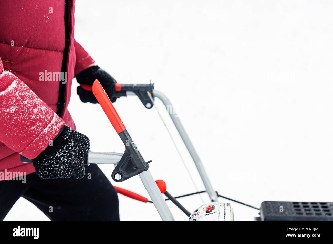 Mann mit roter Schneefräse im Freien. Schnee in der Nähe des Hauses vom Hof entfernen Stockfoto