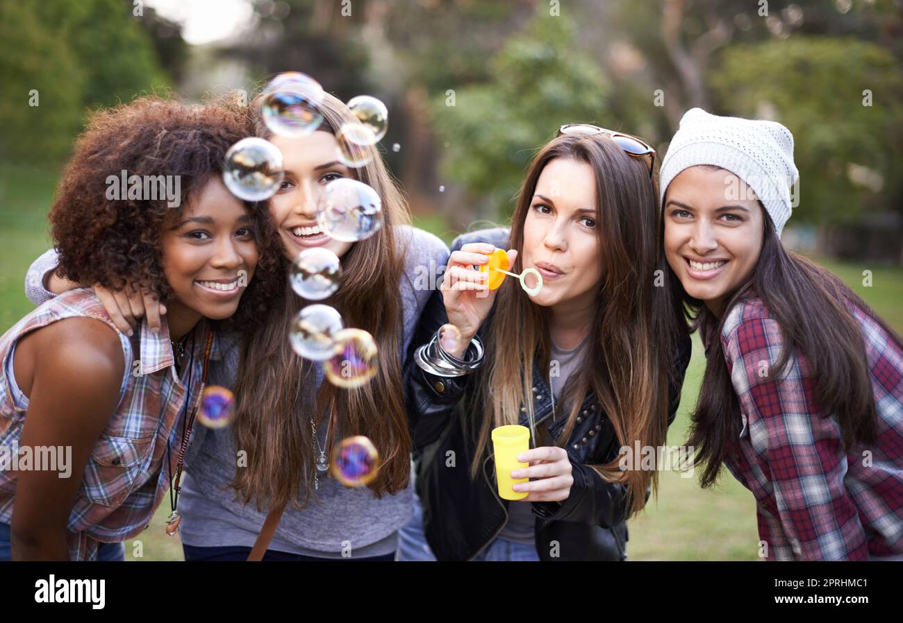 Eine Gruppe von Freunden genießt einen Tag im Park mit Blasen Stockfoto